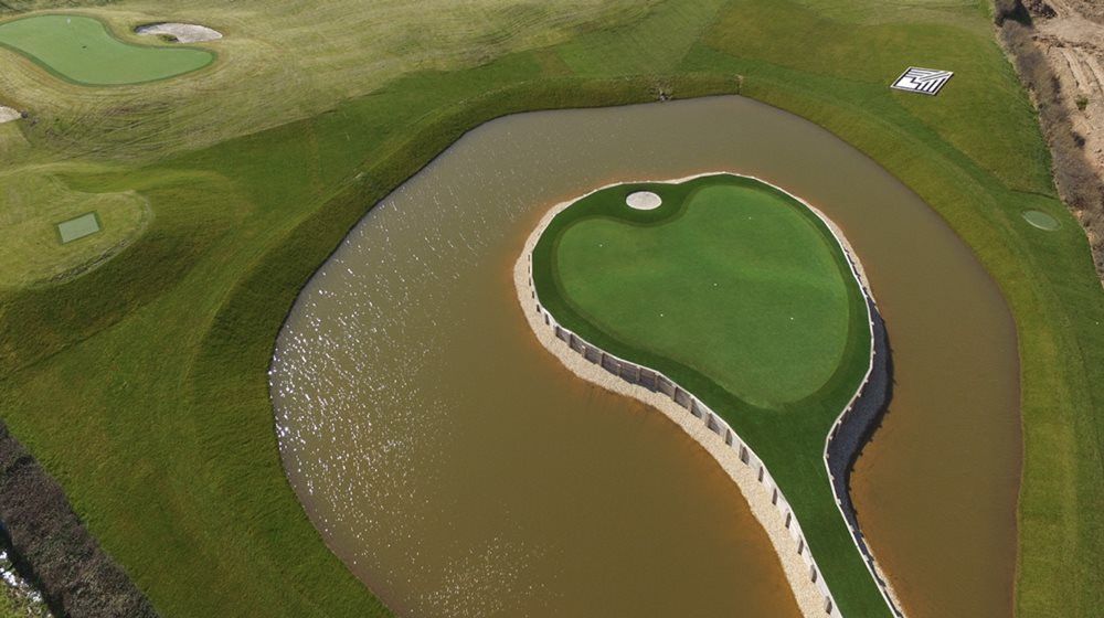 Las Vegas Aerial view of a vibrant green synthetic grass island in a natural pond on a golf course